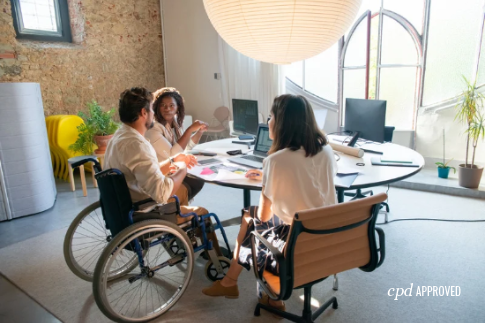 workspace with three people working at a table, one of them in a wheelchair